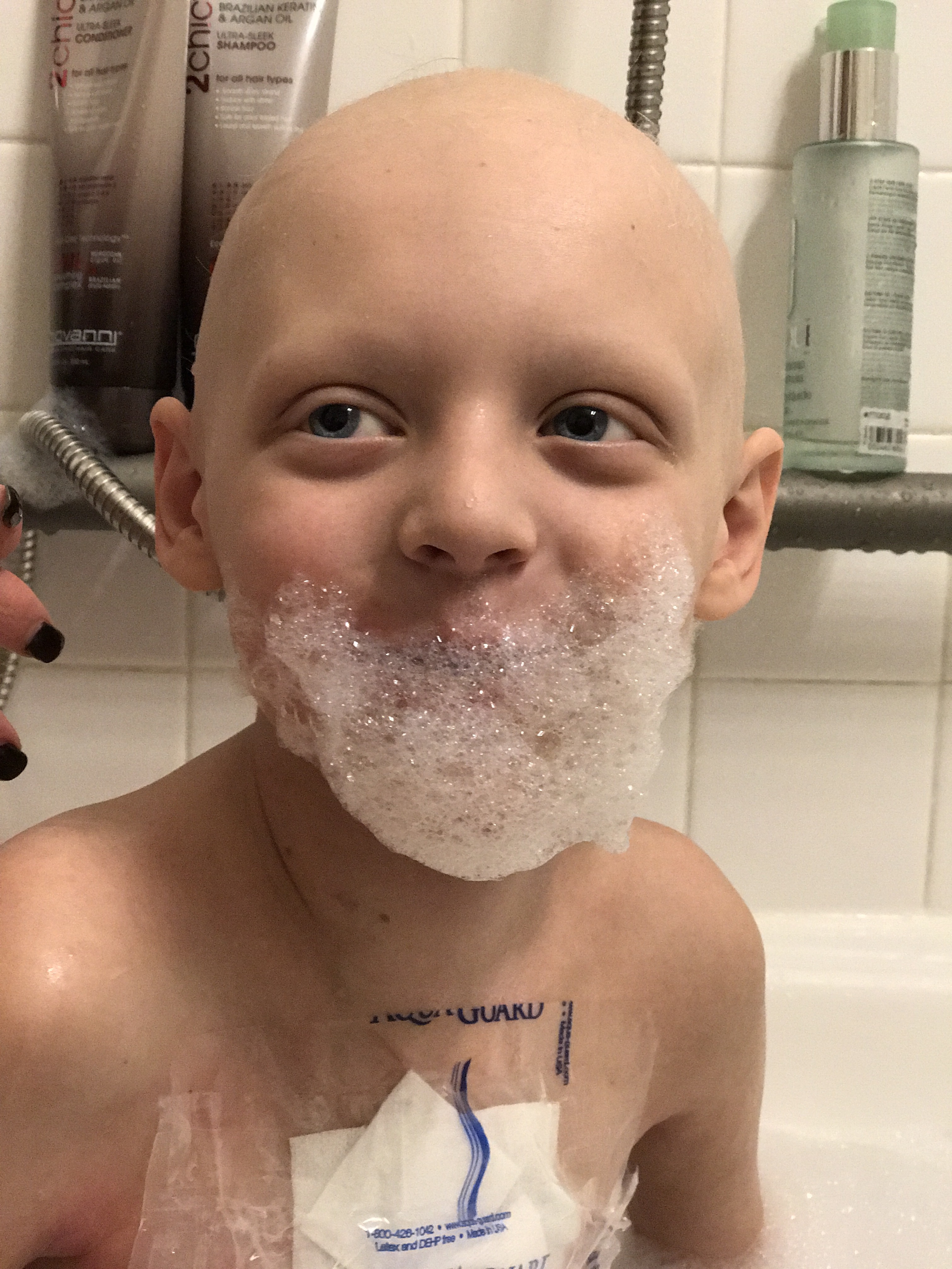 Max smiling with a soap bubble beard while receiving a bath