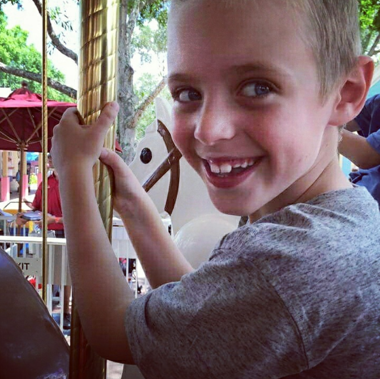 Max smiling while riding on a merry-go-round